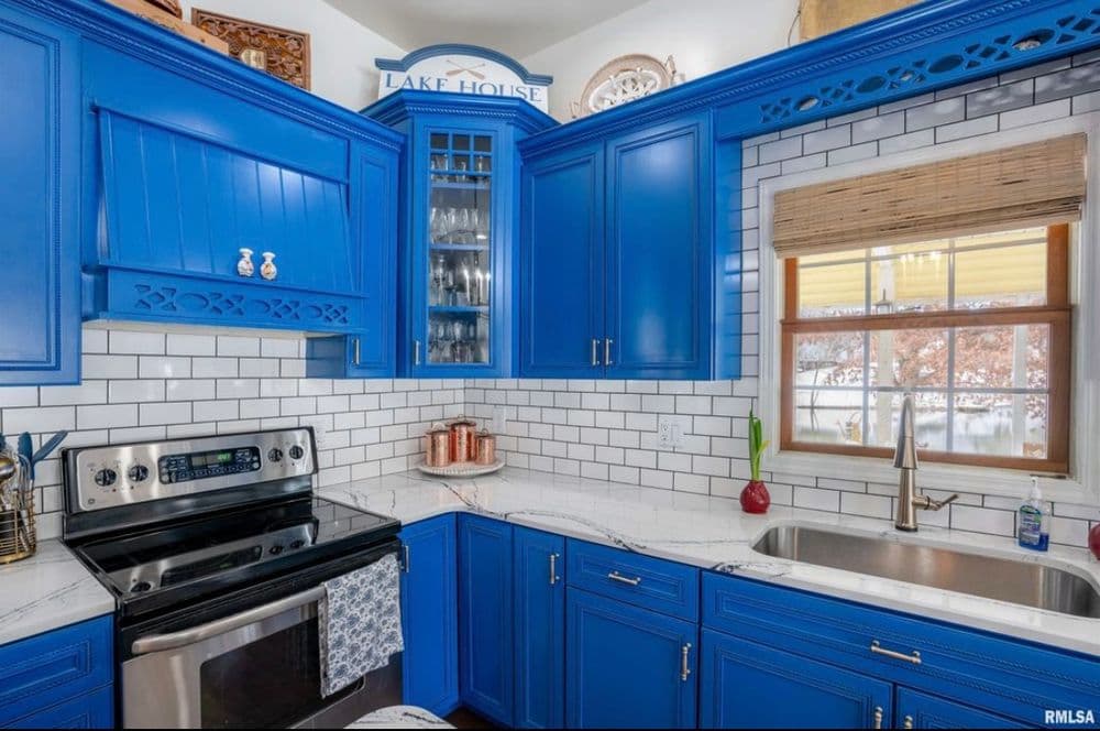 Bright blue kitchen with modern appliances, white subway tile, and lake house decor accents.