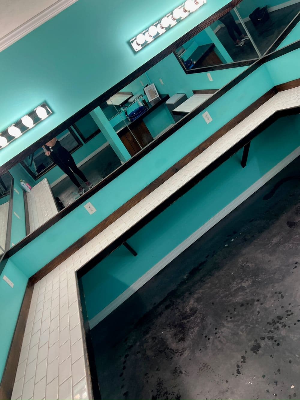 Bright turquoise room with multiple mirrors and a tiled counter, ideal for makeup or styling.