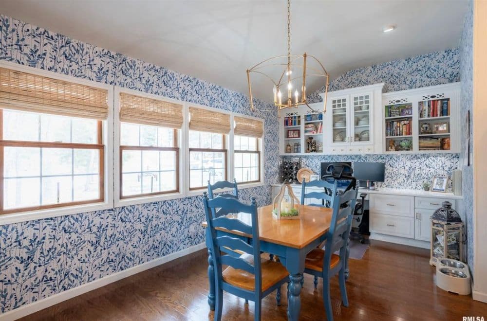 Bright and inviting dining area with blue chairs, wood table, and patterned wallpaper.