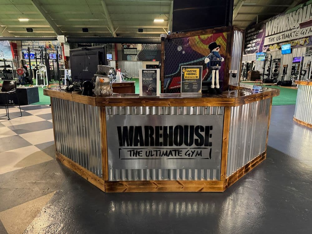 Warehouse gym reception area with rustic wood and metal design, showcasing fitness resources.