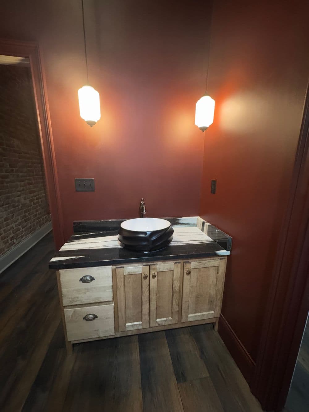 Modern bathroom featuring a stylish wooden vanity with a black bowl sink and warm pendant lights.