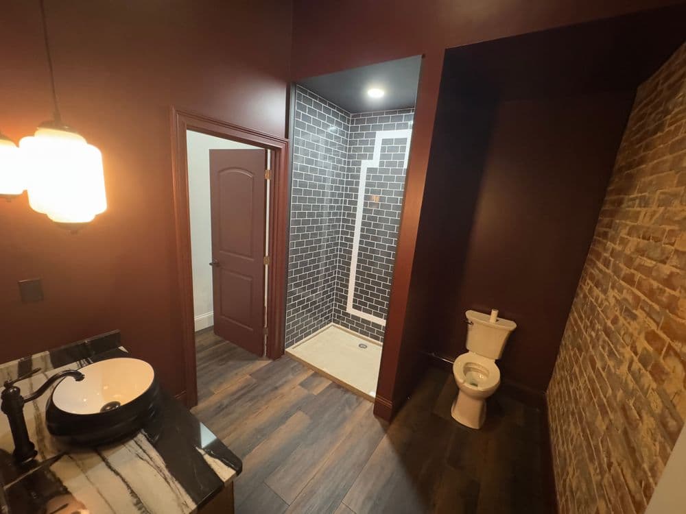Modern bathroom with dark walls, stylish shower, and sleek sink.