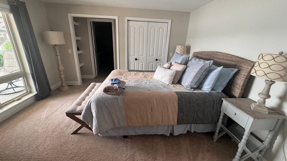 Cozy bedroom with a large bed, decorative pillows, and natural light from a window.