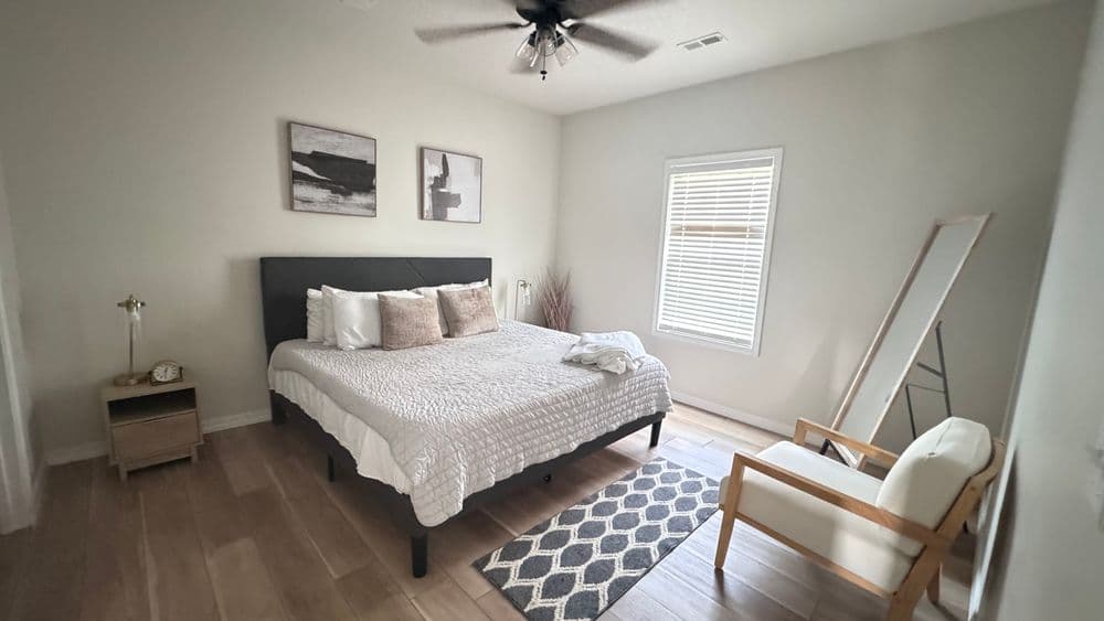 Cozy modern bedroom with a queen bed, natural light, and stylish decor elements.