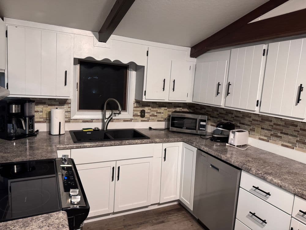 Modern kitchen with white cabinets, granite countertops, and stainless steel appliances.
