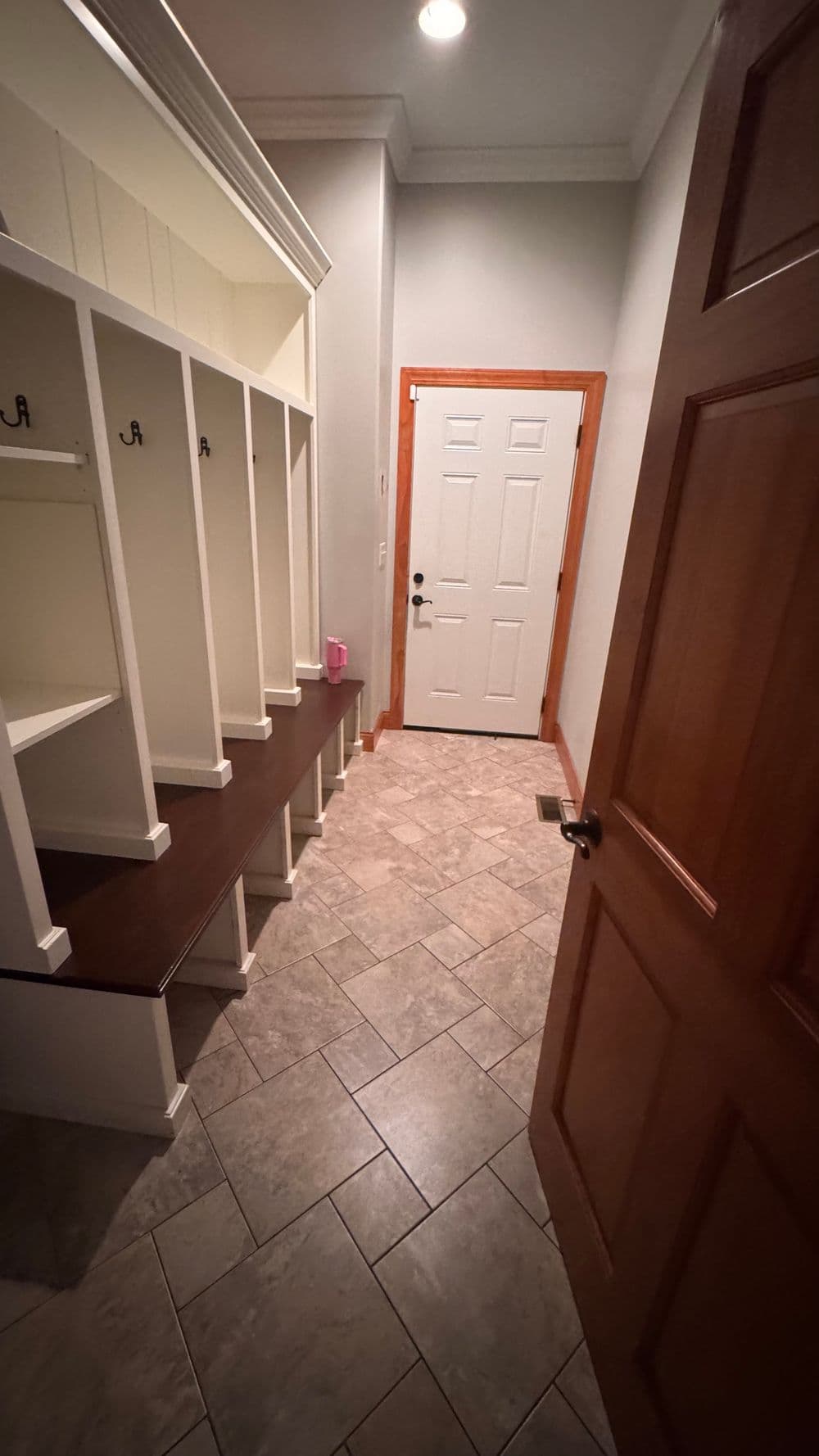 Entryway with built-in storage cubbies, door, and tiled flooring, well-lit.