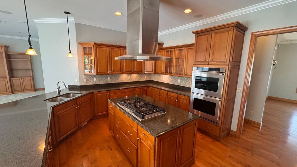 Spacious modern kitchen with wooden cabinets, granite countertops, and stainless steel appliances.